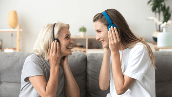 woman and daughter at home using headphones