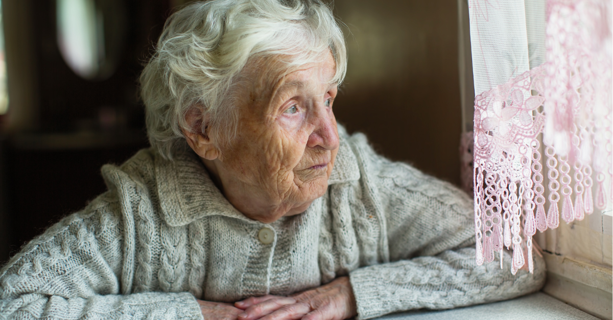 older woman looking out window at home