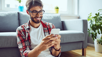 man at home smiling on his mobile phone