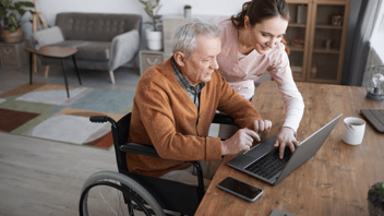 Elderly man in wheelchair at laptop
