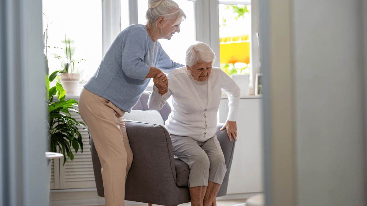 woman helping to get elderly woman off chair