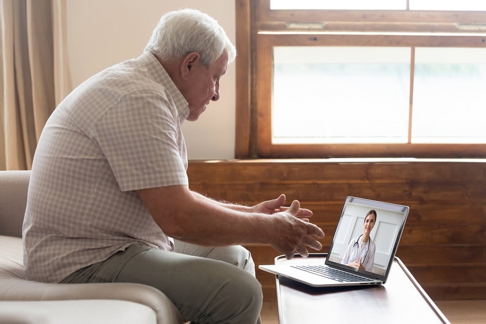 man sitting at laptop speaking to doctor